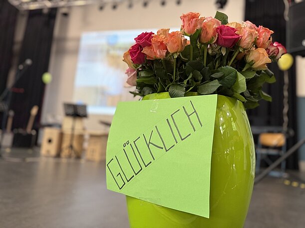 Grüne Vase mit Rosen und Schild „Glücklich“ bei der Entlassungsfeier