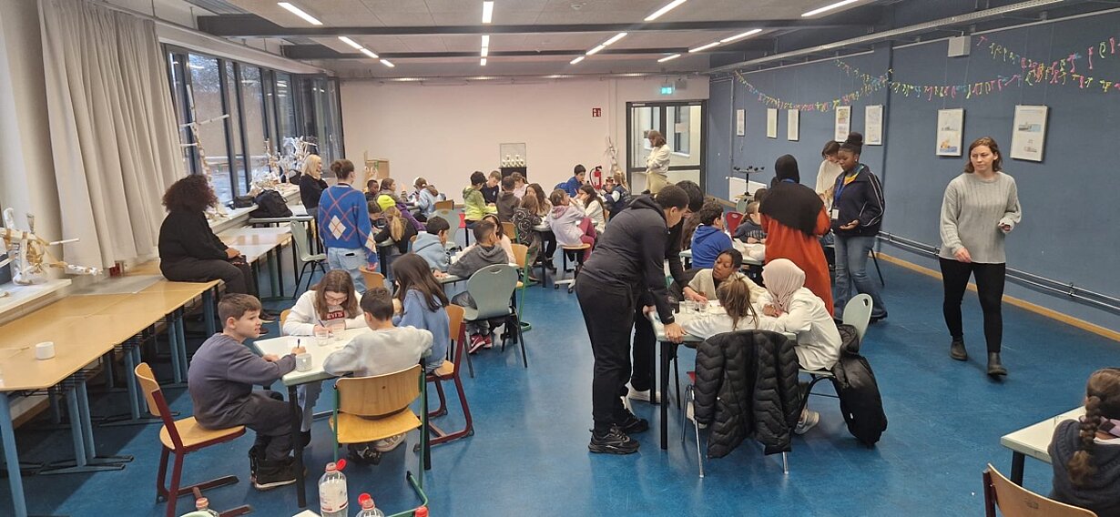 Grundschulkinder rechnen und knobeln an Gruppentischen im MZE