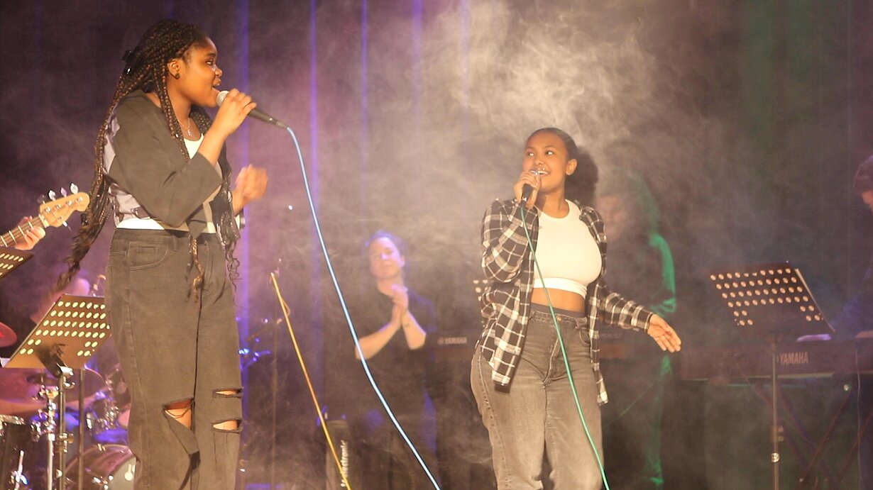 Zwei Sängerinnen singen im Bühnennebel bei The Voice of Wilhelmsburg
