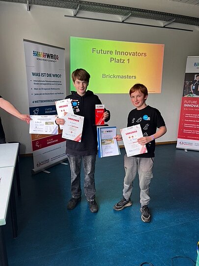 Team Brickmasters Jan und Juri aus der 5c mit Urkunden vor Folie „Platz 1“