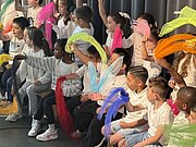 Kinder mit bunten Bändern und Perücken beim Sommerfest