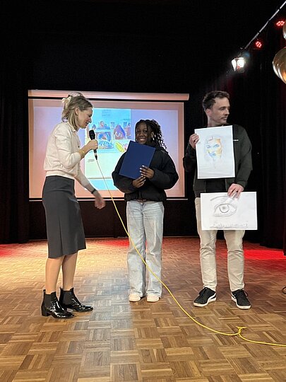 Schülerin mit Urkunde zwischen zwei Lehrkräften auf der Bühne bei Like a Star