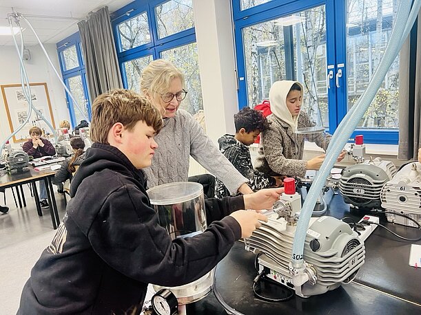 Schüler und Betreuerin an einer Vakuumpumpe im DESY-Schülerlabor