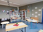 Neu eingerichtete Bücherei mit Regalen, Tischen und Sofa