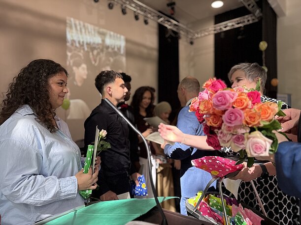 Absolventin nimmt bei der Entlassungsfeier Rosen entgegen