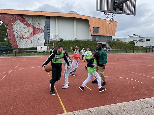Basketballspiel auf rotem Hartplatz vor Kletterwand