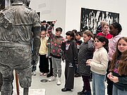 Schülergruppe neben einer Bronzestatue in einer Kunsthalle