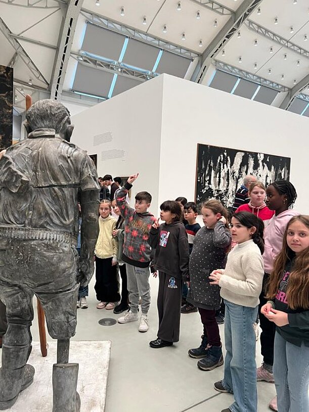 Schülergruppe neben einer Bronzestatue in einer Kunsthalle