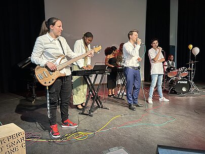 Musikgruppe mit Bass, Keyboard und Gesang auf der Bühne