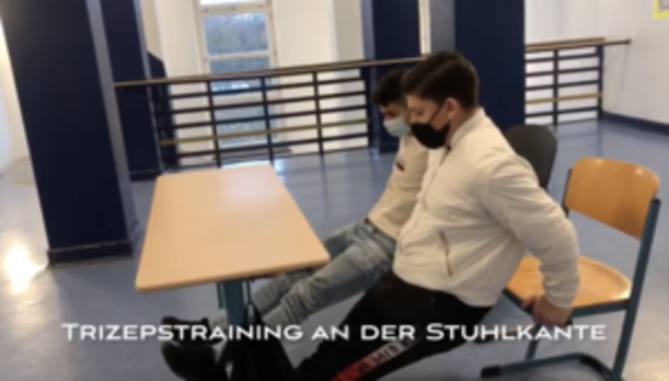 Schüler zeigt Trizepstraining an der Stuhlkante im Schulflur