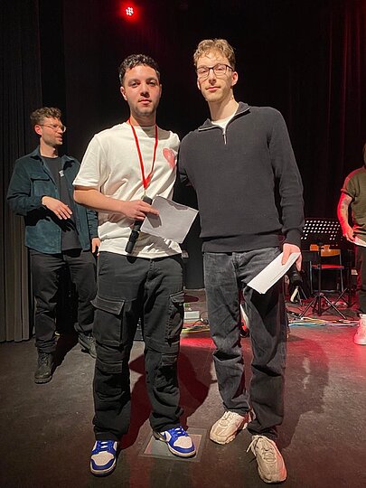Zwei junge Männer mit Moderationskarten auf der Bühne