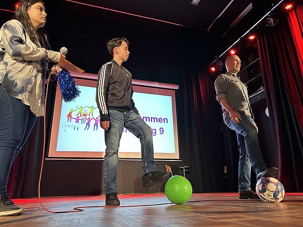 Schüler und Lehrer zeigen Balltricks mit Fußball auf der Bühne