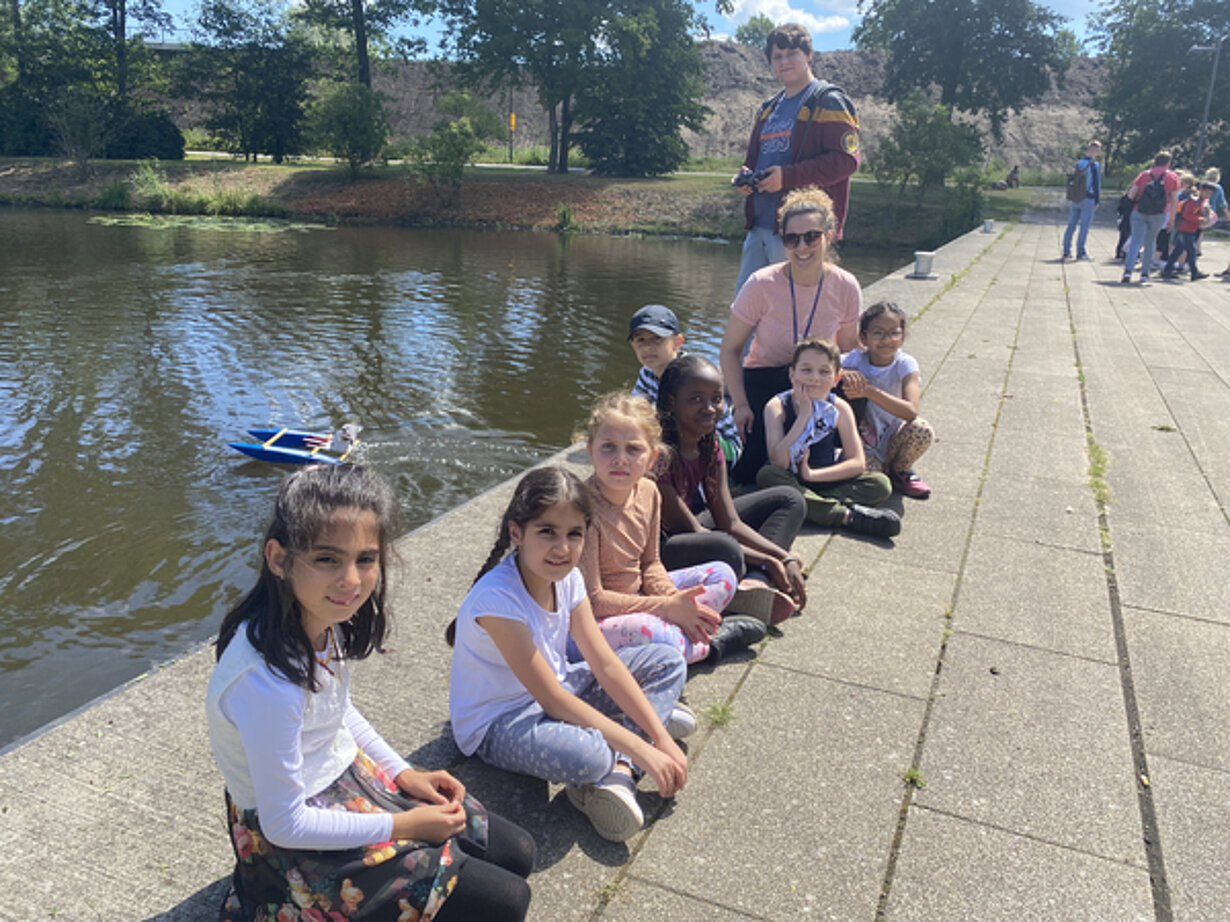Kinder und Profilschüler sitzen am Kanal beim Bootstest