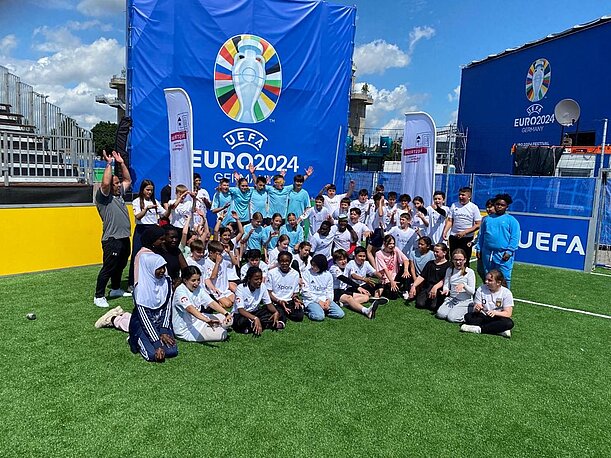 Große Schülergruppe vor UEFA-Euro-2024-Kulisse auf Kunstrasen