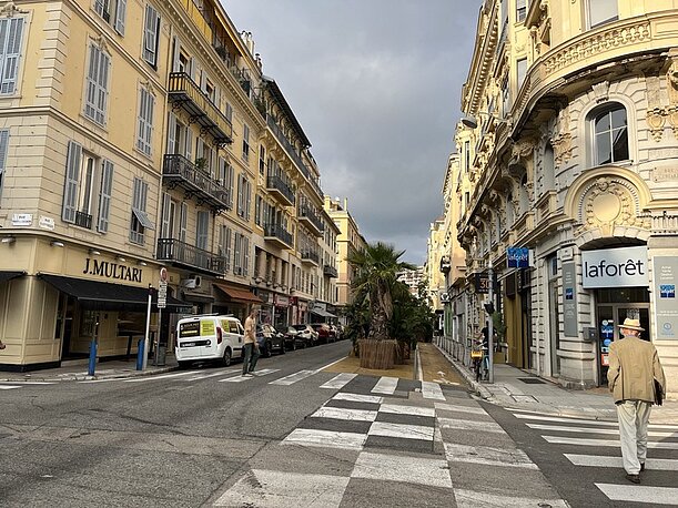 Straße mit hellen Altbaufassaden und Zebrastreifen in der Innenstadt von Nizza