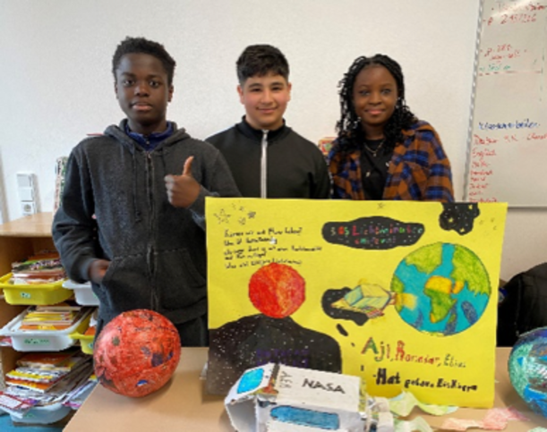 Drei Jugendliche mit Plakat zu Erde und Mars zur Frage nach einem Planet B