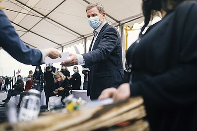 Mann im Anzug nimmt beim Spreehafenfest unter einem Zelt eine Karte entgegen