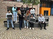 Jugendliche und Erwachsene mit gespendeten Laptops vor dem Schulgebäude