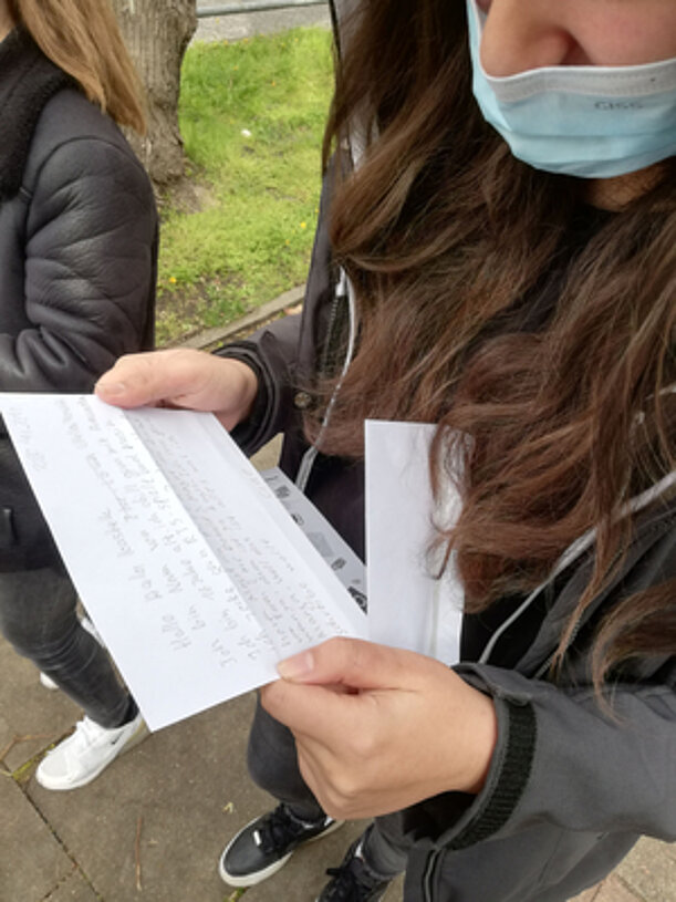 Schülerin liest einen handgeschriebenen Brief im Freien