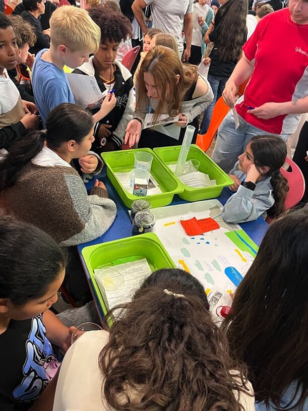 Kinder beobachten Experimente zum Wasserkreislauf in Wannen