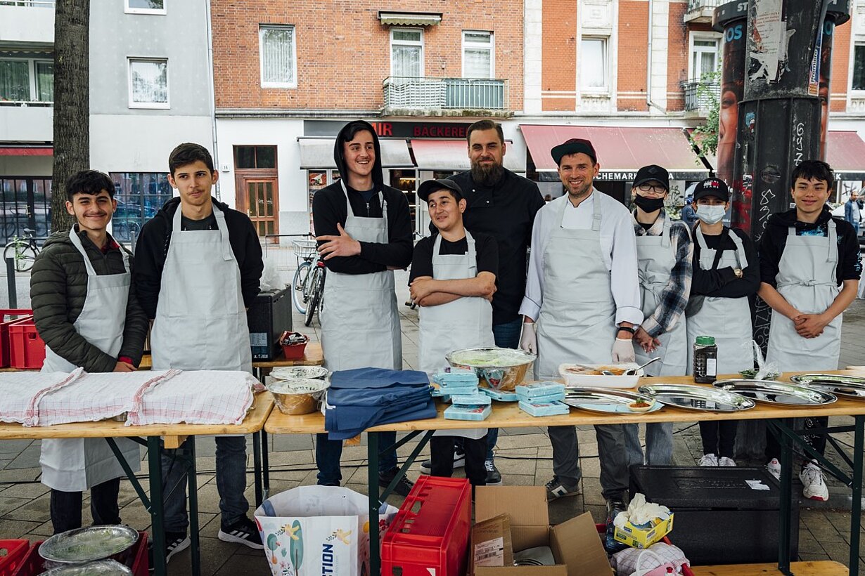 Schülerinnen und Schüler in Schürzen am Buffet beim Stadtteildinner