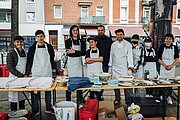 Schülerinnen und Schüler in Schürzen am Buffet beim Stadtteildinner