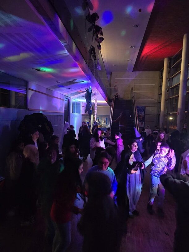 Tanzende Kinder im lila beleuchteten Foyer bei der Halloween-Party