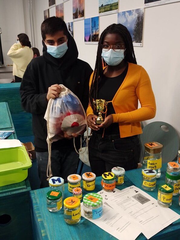 Zwei Jugendliche mit Pokal und Gläsern am Stand des ScienceCafés