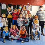 Vorschulkinder und Jugendliche mit gebastelten Tigermasken im Klassenraum