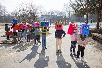 Vorschulkinder mit bunten Kastenmasken auf dem Schulhof