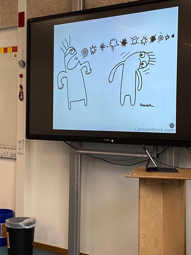Cartoon mit zwei Figuren und Schimpfwort-Symbolen auf einem Bildschirm