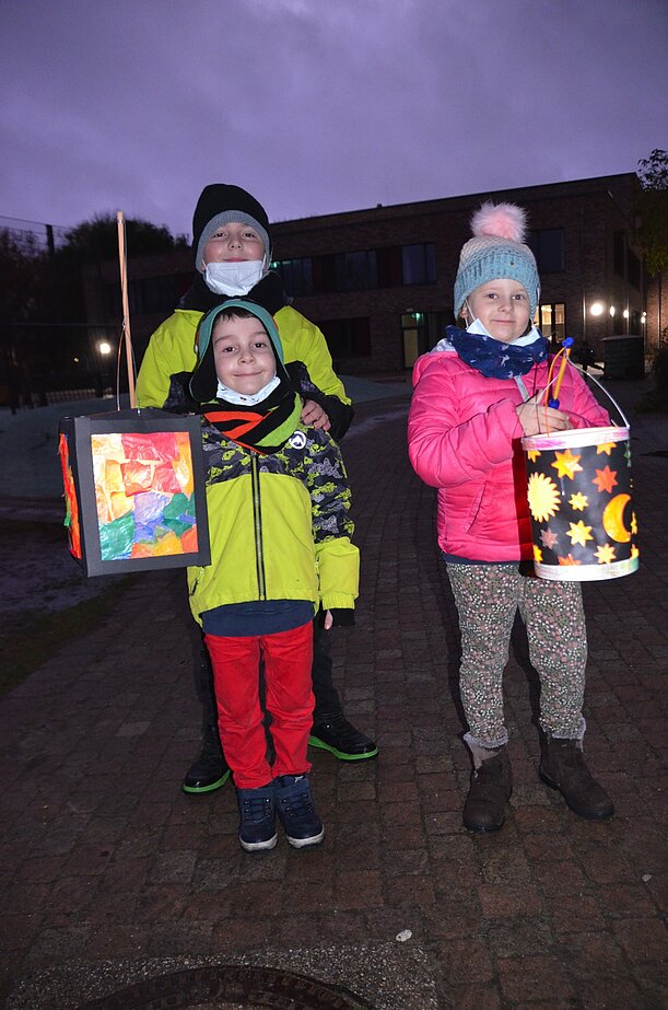 Zwei Kinder mit bunten selbstgebastelten Laternen am Abend