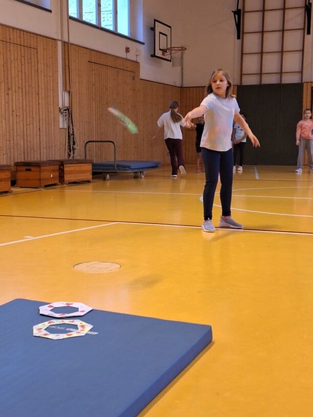 Kind der 4c wirft ein Papier-Frisbee in der Sporthalle beim MINT-Wettbewerb