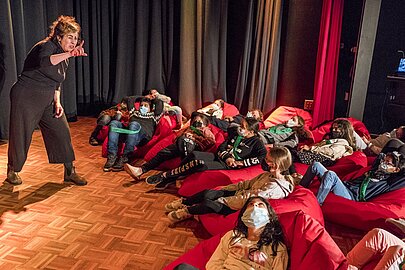 Darstellerin gestikuliert vor Kindern auf Sitzsäcken beim Kinderkonzert