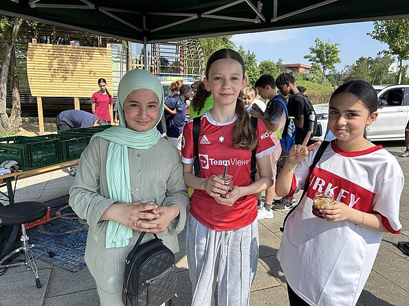 Tuqa, Hajrije und Nisa mit Getränken unter einem Pavillon im Inselpark