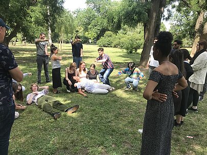 Jugendliche liegen und sitzen gemeinsam auf einer Wiese in einem Prager Park