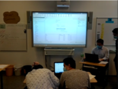Schüler an Laptops vor einem Smartboard mit RPA-Software