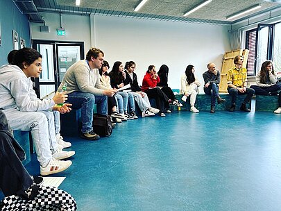 Jugendliche und Politiker im Gespräch auf blauen Sitzwürfeln