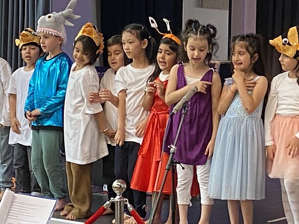 Kostümierte Vorschulkinder singen am Mikrofon bei der Tiefsee-Aufführung