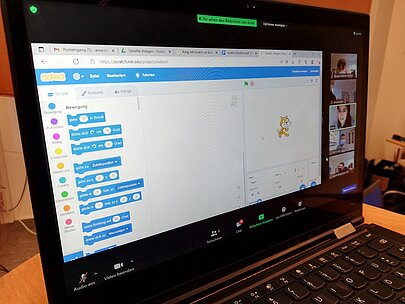 Nahaufnahme Laptopbildschirm mit Scratch-Codeblöcken und Katzenfigur