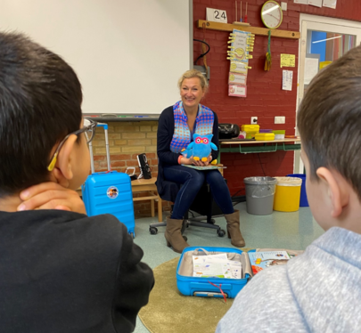 Frau Ellenberg von coach@school stellt Grundschulkindern den Bücherkoffer vor
