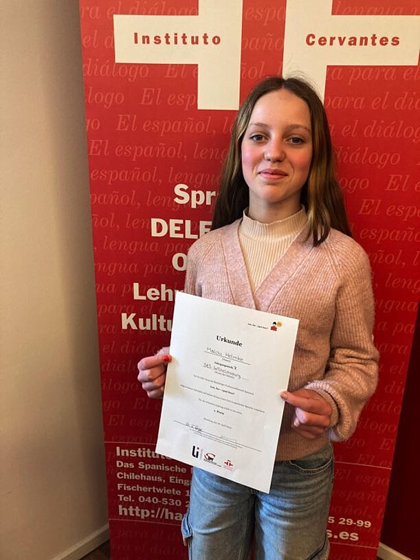 Malou hält beim Instituto Cervantes ihre Urkunde für den Spanisch-Lesewettbewerb