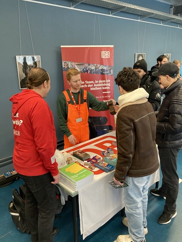 Jugendliche informieren sich an einem Ausbildungsstand mit Broschüren
