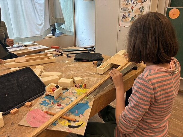 Schülerin baut in der Werkstatt ein Holzboot