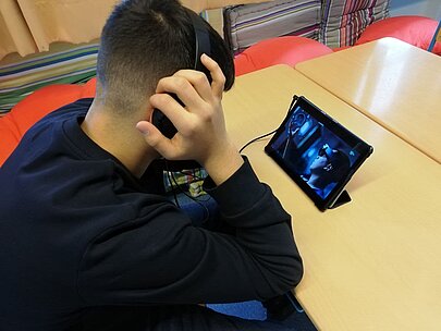 Schüler hält Kopfhörer, daneben Tablet mit VR-Anwendung zur Berufsorientierung