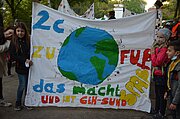 Kinder mit Transparent „2c zu Fuß – das macht Spaß“ und Erdball