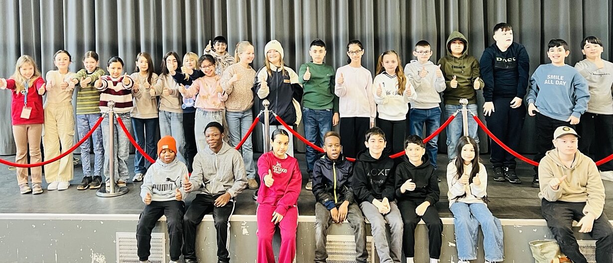 Gruppenfoto der Teilnehmenden der Jahrgänge 4 und 5 auf einer Stufe