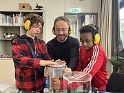 Schüler mit Gehörschutz experimentieren mit Glasglocke im DESY-Vakuumlabor
