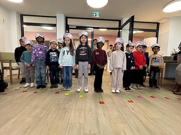 Vorschulkinder mit Papierhüten stehen in einer Reihe