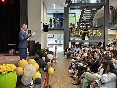 Redner am Pult vor vollem Saal bei der Entlassungsfeier